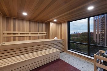 A wooden sauna room with a view of the city outside the window.